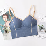 Blue bralette with beige straps on a surface with magazines and a bottle of perfume.
