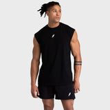 Man wearing a black sleeveless shirt and shorts with a logo on a light gray background