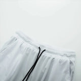 Close-up of white shorts with a black drawstring on a light gray background