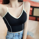 Person wearing a black tank top with white trim and denim shorts.