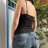 Person wearing a black lace tank top and blue jeans with a blurred background