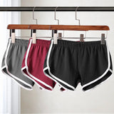 Three pairs of shorts hanging on a rack with a white background