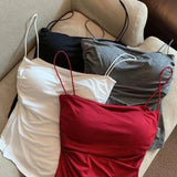 Three dresses in white, red, and gray on hangers against a beige sofa.