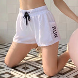 White athletic shorts with 'RUN' printed on the side, worn by a person on a tiled floor.