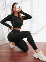 Person wearing a black athletic outfit taking a selfie in a room with wooden flooring.