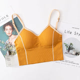 Yellow bralette on a magazine with a floral arrangement and perfume bottle.