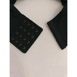 Black strapless bra with metal hooks on a textured white surface