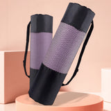 Black yoga mat bag with mesh side on a pink platform