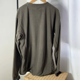 Brown textured sweater on a hanger against a white wall
