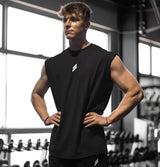 Muscular man in a black sleeveless shirt standing in a gym.