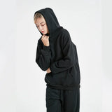 Person wearing a black hoodie and pants on a white background