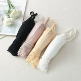 Set of four folded lace umbrellas in black, pink, yellow, and white on a light surface.