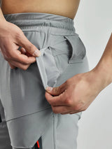 Person adjusting gray athletic shorts with a white background