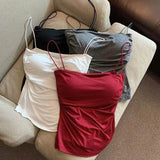 Three dresses in white, red, and gray on a beige couch.