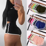 Woman taking a mirror selfie wearing black athletic shorts with white trim, surrounded by color options on hangers.