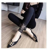Person wearing black shoes with gold accents sitting on a wooden floor.
