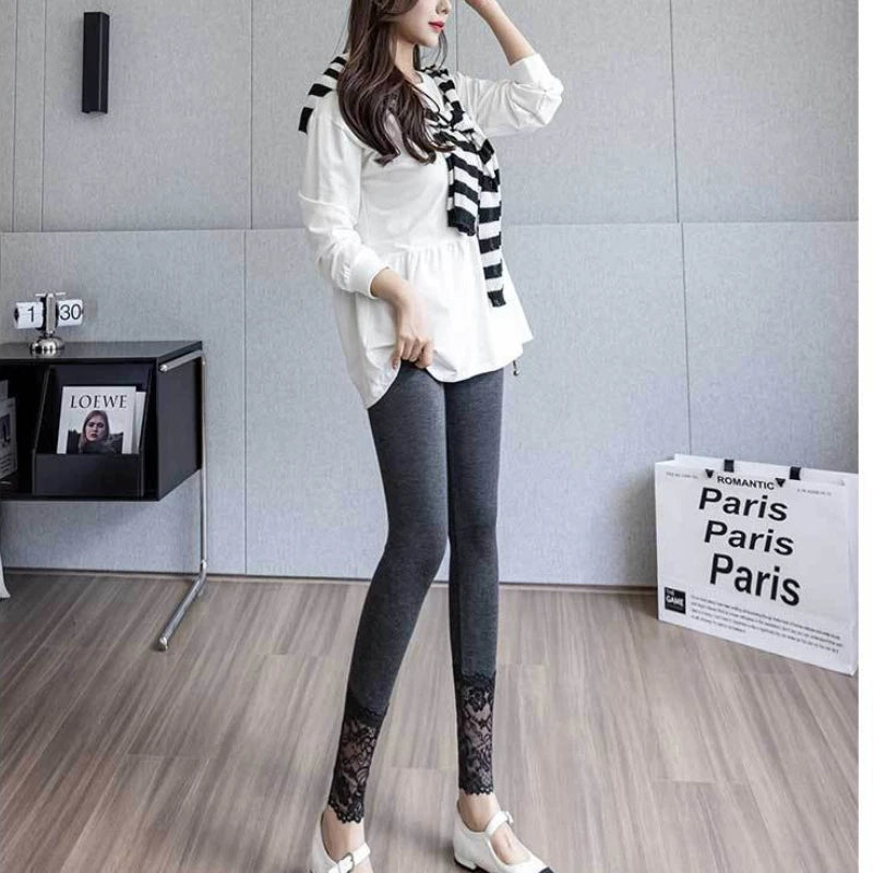 Woman wearing gray high waist leggings with lace trim and slim fit shape, paired with a white blouse and striped scarf.