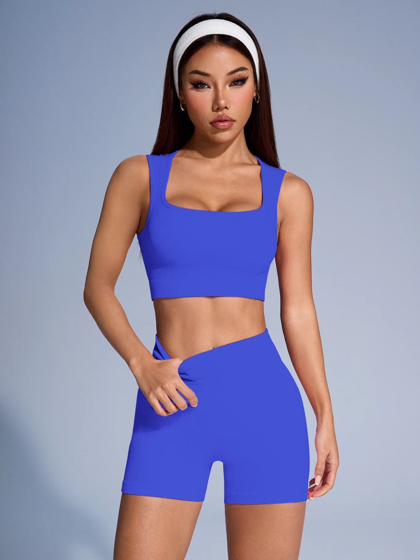 Woman wearing a blue athletic seamless ribbed workout set with crop tank and shorts by Athletic Sanctuary.