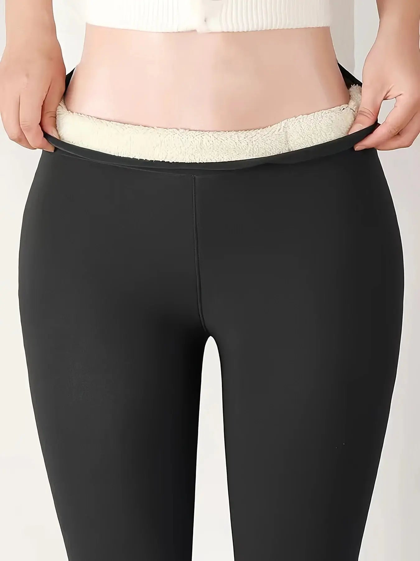 Black women's high-waisted winter leggings with white lining, featuring soft stretch fabric, worn by a model on a plain background.