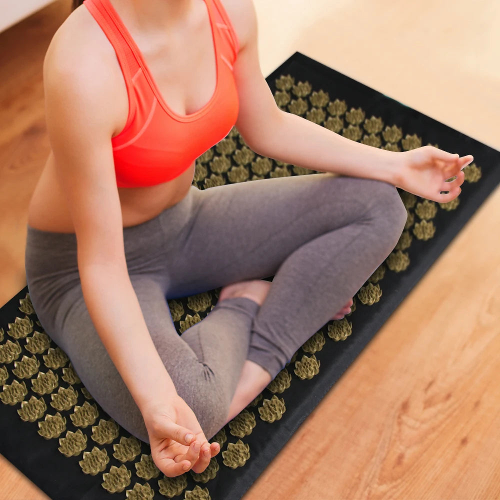 Person sitting on black Athletic Sanctuary acupressure massage mat and cushion set for stress relief and back pain relief.